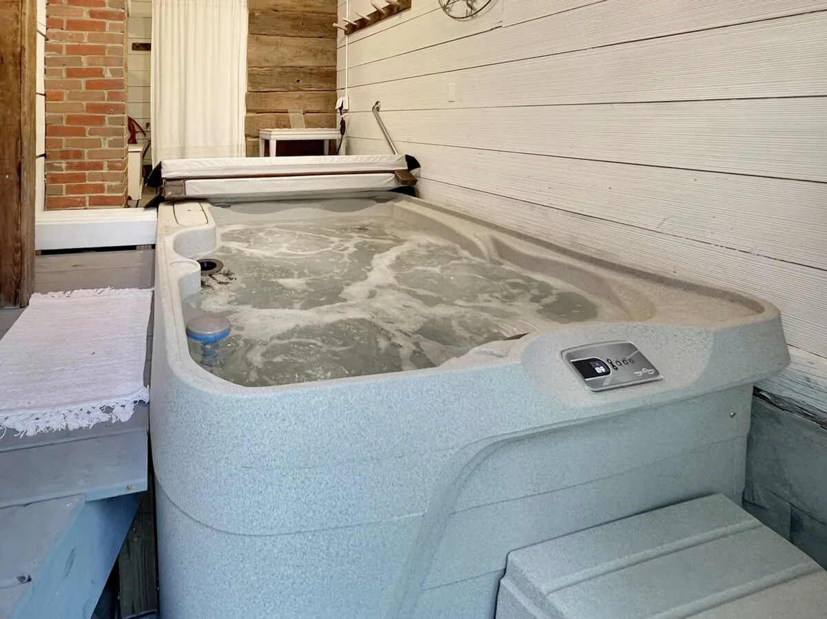 A tranquil indoor hot tub setup, bordered by wooden and brick walls. The space offers a secluded, rejuvenating spot to soak after a day spent outdoors in the snow.